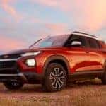 Red and white 2021 Chevrolet Trailblazer ACTIV parked in a field with a blue and pink sky in the background