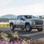 A silver 2020 Chevy Silverado 2500HD Z71 is parked in front of a majestic horse farm.