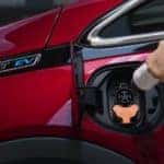 A closeup is shown of a red 2020 Chevy Bolt being charged.