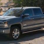 Dark 2017 Chevrolet Silverado pickup truck park on a dirt path near a fence