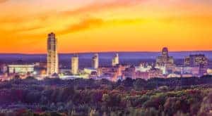 Albany NY skyline behind orange and red fall trees and in front of an orange sky