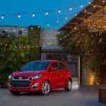Red 2020 Chevrolet Spark next to a building that has lights hanging off of it