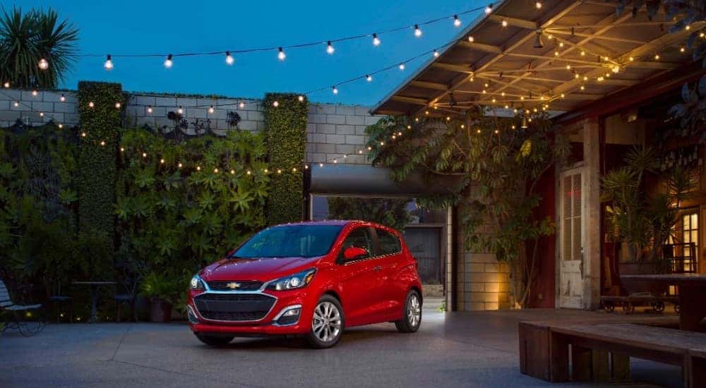 Red 2020 Chevrolet Spark next to a building that has lights hanging off of it