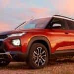Red 2021 Chevrolet Trailblazer with a white roof, parked in a field with a blue and pink sky behind it