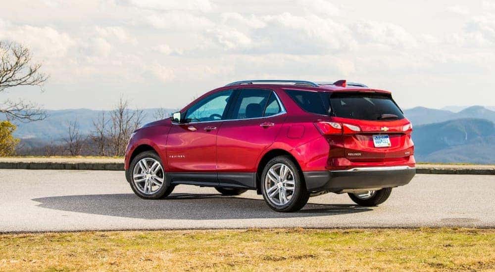 A red 2020 Chevy Equinox from a Chevy dealership near Clifton Park, NY, is parked on a hill against a cloudy sky.