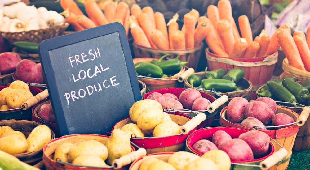 A chalkboard that reads 'fresh local produce' is placed among baskets of vegetables.