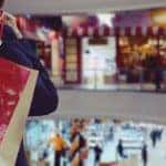 A woman is holding bags over her shoulder and looking over a mall in Clifton Park,