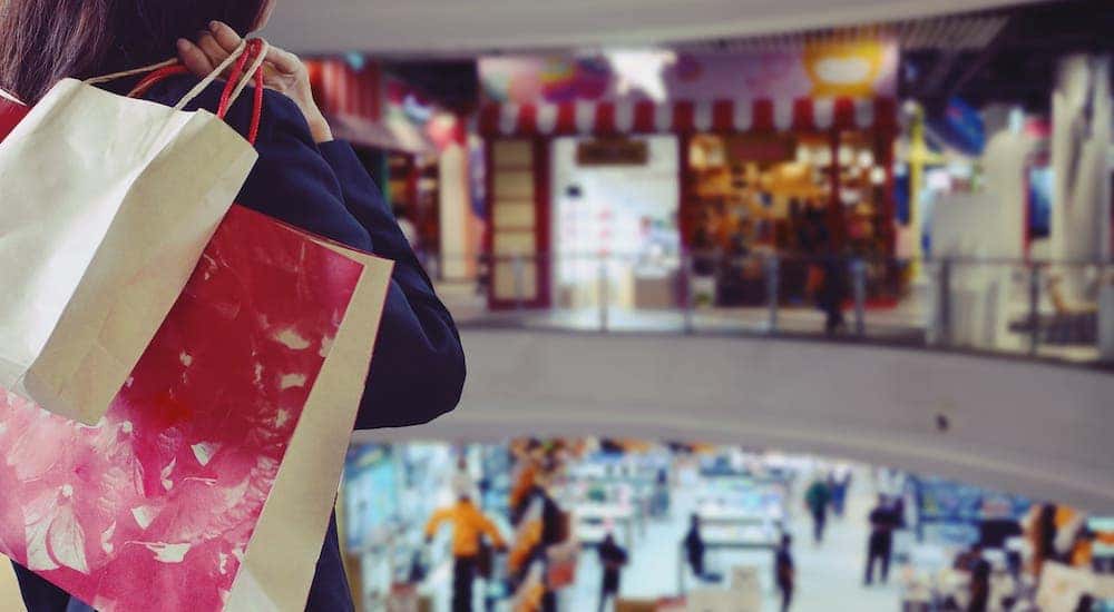 A woman is holding bags over her shoulder and looking over a mall in Clifton Park,