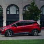 Red 2020 Chevrolet Bolt EV SUV parked in front of a stone building with black windows