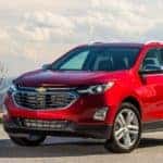 Red 2020 Chevrolet Equinox SUV parked on a road, near a cliff, with mountains and plants in the background