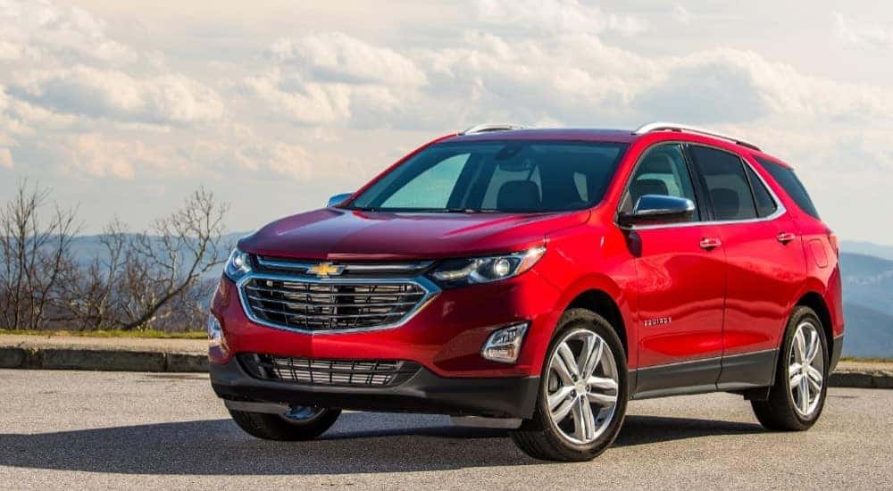Red 2020 Chevrolet Equinox SUV parked on a road, near a cliff, with mountains and plants in the background