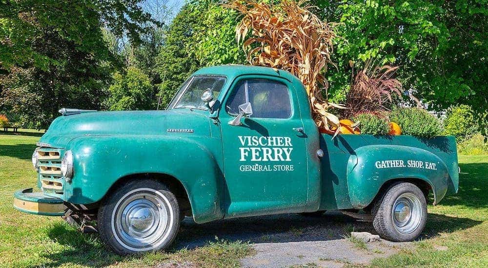 An antique green truck full of fall decorations is shown with Vischer Ferry General Store printed on the side.
