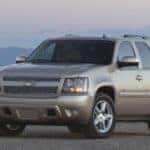Tan 2009 Chevrolet Tahoe parked on pavement in front of tall mountains