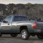 Grey 2009 Chevrolet Silverado parked in a dirt lot in front of tall rocky hills