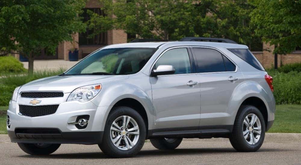 Silver 2010 Chevrolet Equinox SUV on the street near green trees