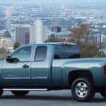 Blue 2013 Chevrolet Silverado pickup truck parked in front of a city skyline