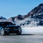 Black 2016 Chevrolet Camaro parked on open ground in front of tall rocky hills