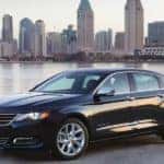 Black 2016 Chevrolet Impala sedan parked in front of water and a city skyline