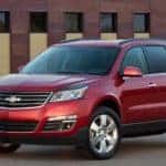 Red 2016 Chevrolet Traverse SUV parked on pavement in front of a brown building