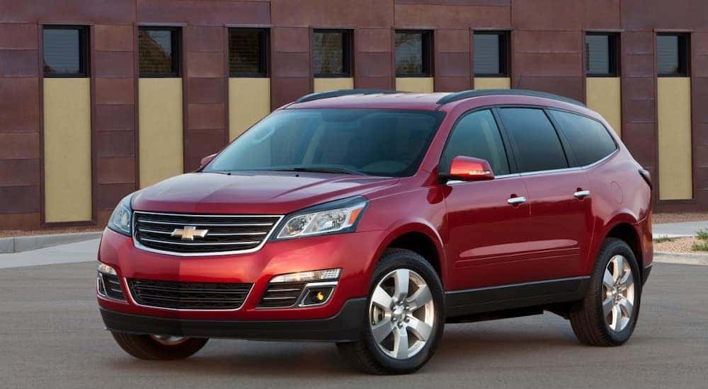 Red 2016 Chevrolet Traverse SUV parked on pavement in front of a brown building