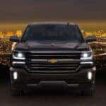 Black 2016 Chevrolet Silverado High Country parked in front of city lights and a dark sky