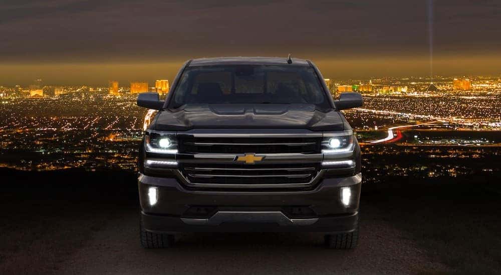 Black 2016 Chevrolet Silverado High Country parked in front of city lights and a dark sky