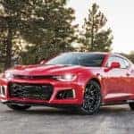 Red 2017 Chevrolet Camaro parked on pavement surrounded by trees