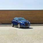 Blue 2017 Chevrolet Trax SUV parked on pavement in front of a brown wall