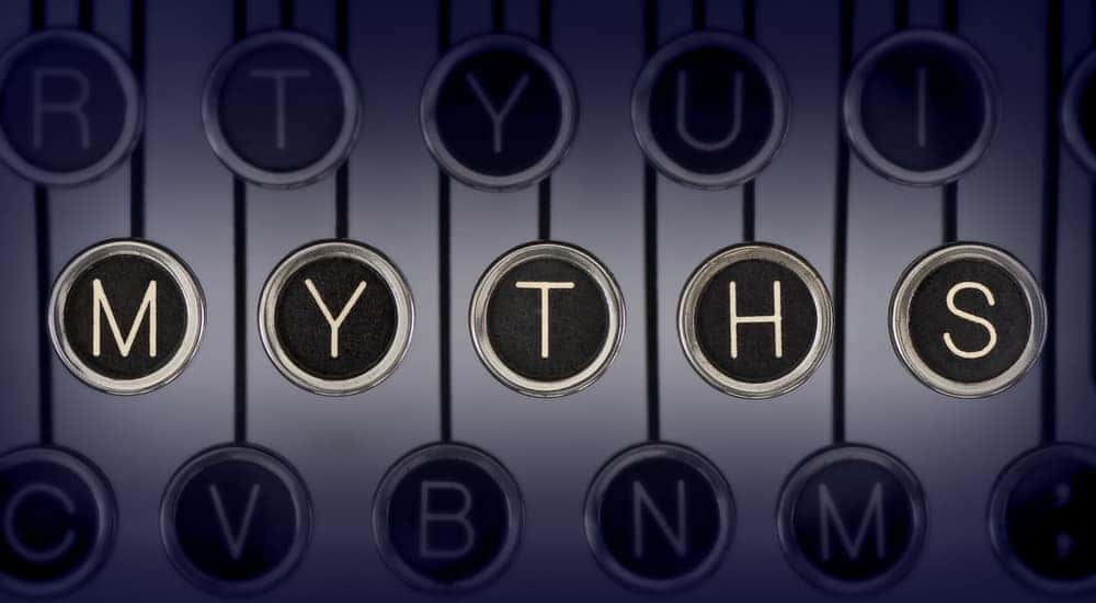 Black and silver letter disks on black strings that spell out "Myths" against a grey background
