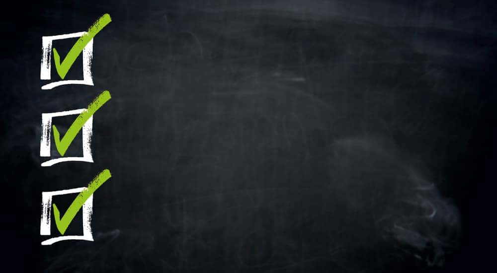 Three white boxes with green check marks in them drawn on a black chalkboard
