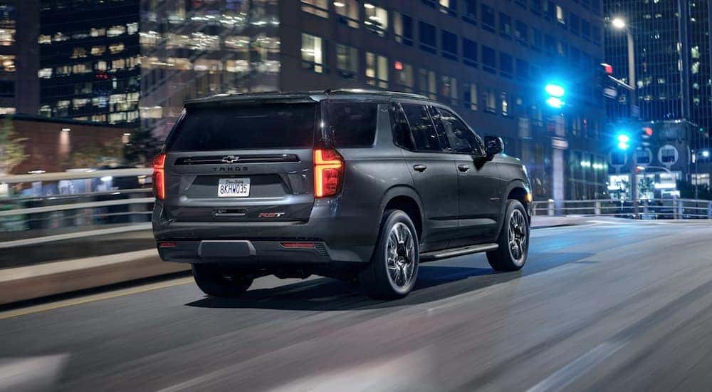 A silver 2021 Chevy Tahoe is driving down a city street after leaving a Chevy Dealership in Clifton Park, NY.