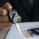 Man in a suit sitting at a desk with a car lease and car keys