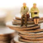 Stacks of coins with figurines of an elderly couple sitting on top of one