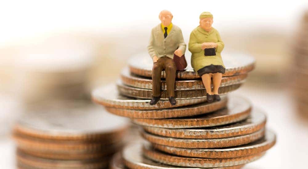 Stacks of coins with figurines of an elderly couple sitting on top of one