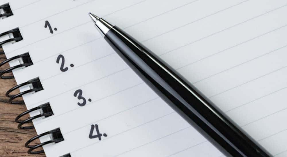 Black pen on top of a notebook with black binding and white lined paper that has black numbers one through four along the side