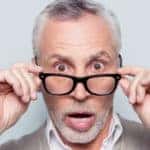 Man pulling down his black glasses with a surprised look on his face