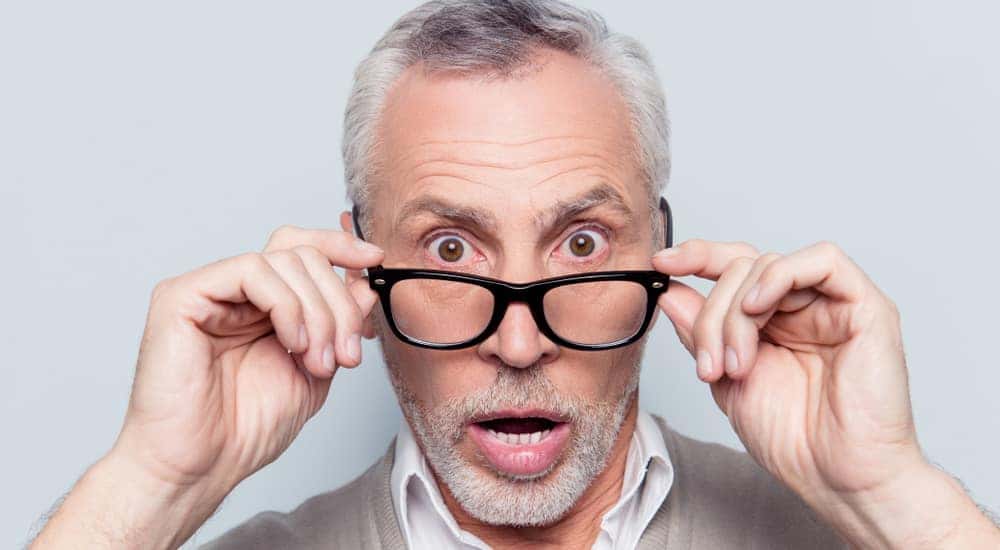 Middle aged man pulling down his glasses with a surprised look on his face