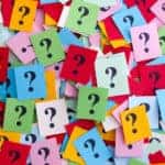 Pile of various color sticky notes with black question marks on them