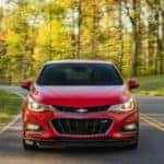 Front view of a red 2016 Chevrolet Cruze on a paved road next to green grass and trees