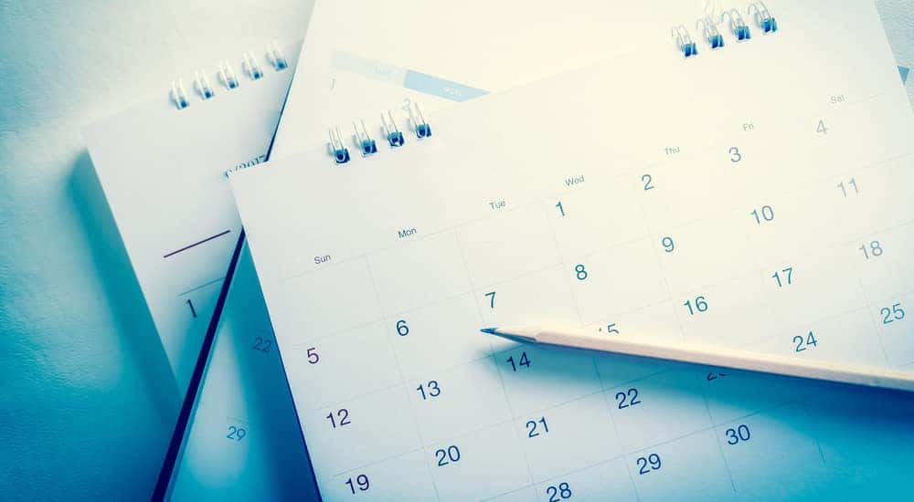 A pencil sitting across a stack of three calendars