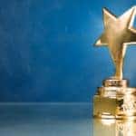 Gold star trophy in smoke against a blue wall