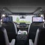 Backseat view of the Chevrolet Suburban interior, highlighting the front infotainment screen and the dual screens for the middle seats