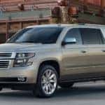 Tan 2018 Chevrolet Suburban parked in front of a brick building
