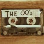 Cassette tape with masking tape on it that says "THE 00's" sitting on a brown table