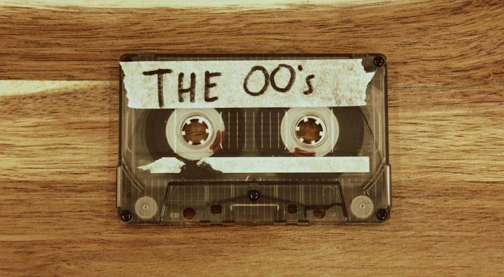 Cassette tape with masking tape on it that says "THE 00's" sitting on a brown table