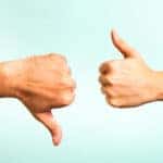 Hand with a thumbs down and hand with a thumbs up against a blue background
