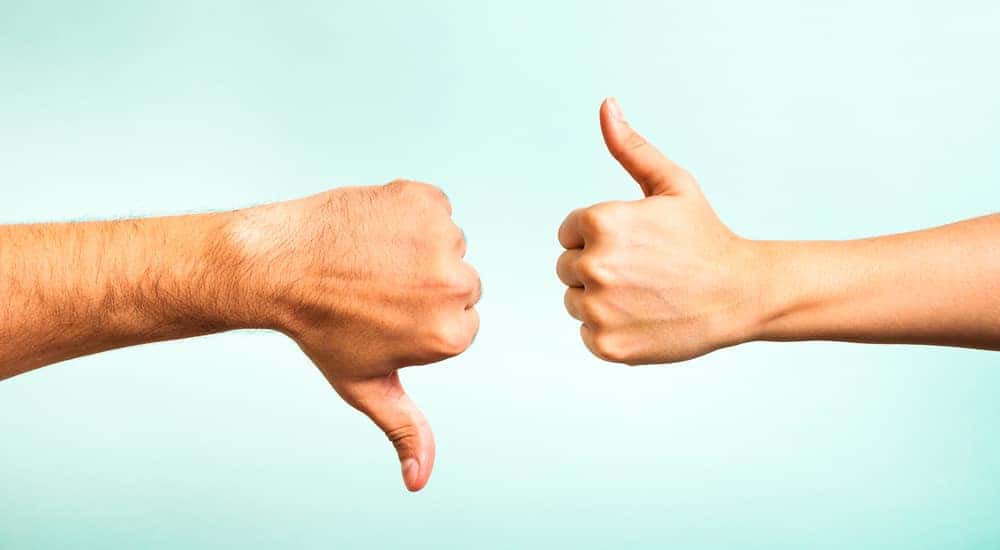 Hand with a thumbs down and hand with a thumbs up against a blue background