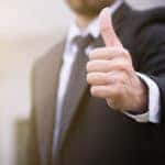 Man in a suit holding his thumb up