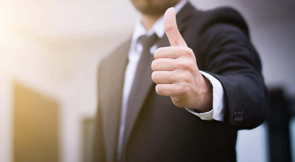 Man in a suit holding his thumb up