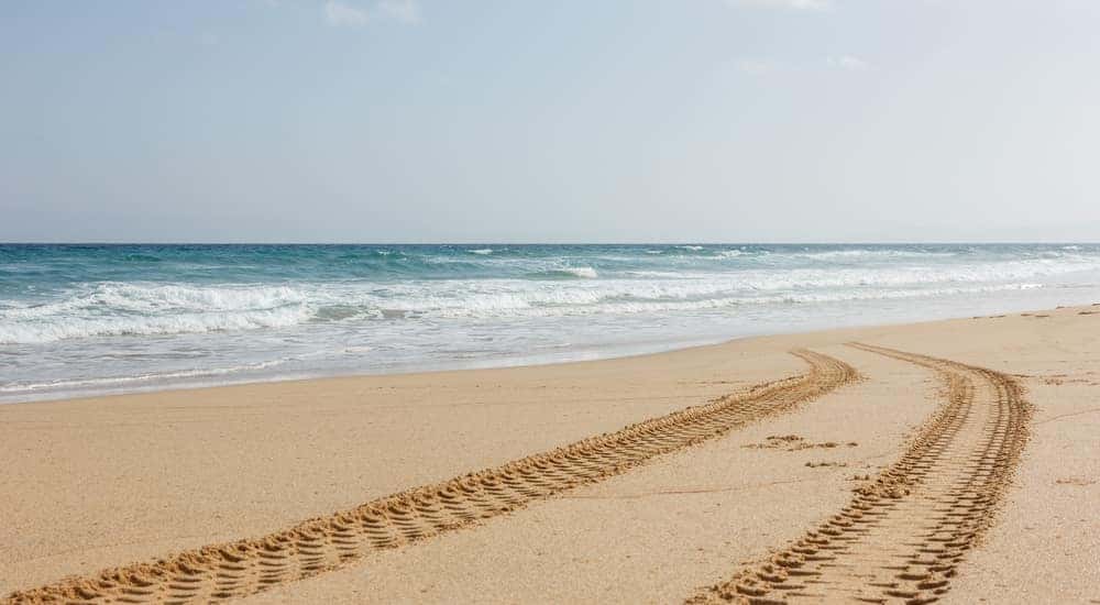 Tire tracks in the sand next to the ocean